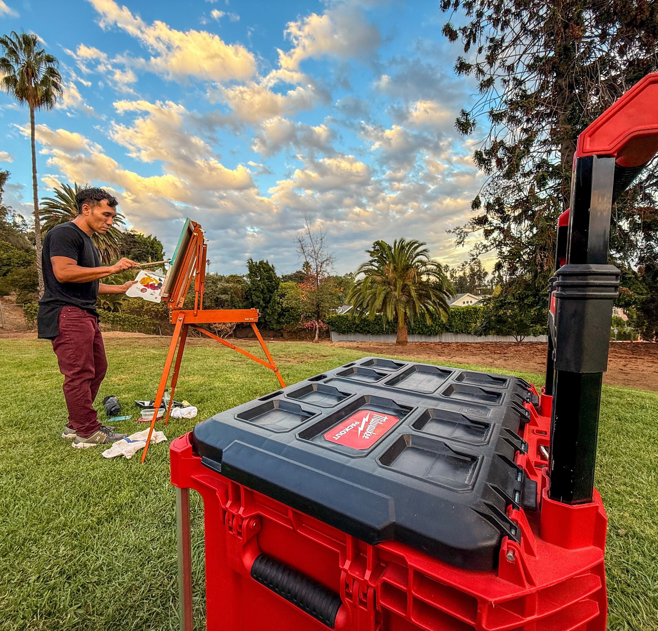 Person painting outdoors near a case